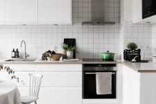 a minimal Scandinavian kitchen with sleek white cabinets, stone countertops and a white square tile backsplash