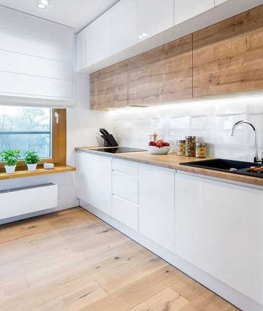 A minimalist Scandi kitchen with wooden upper cabinets, sleek white lower ones, a windowsill shelf and built in lights