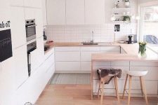 a minimalist Scandinavian kitchen with sleek white cabinets, light staiend countertops, stools and built-in appliances