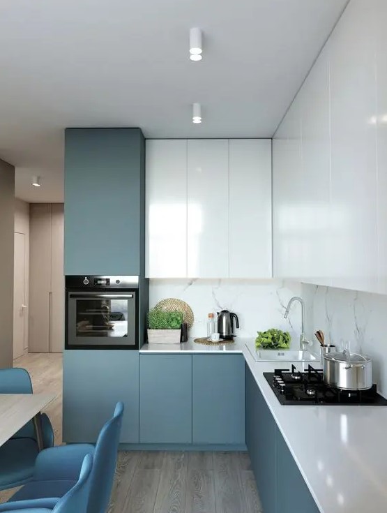 a minimalist blue and white kitchen with a white stone backsplash and white countertops is all chic