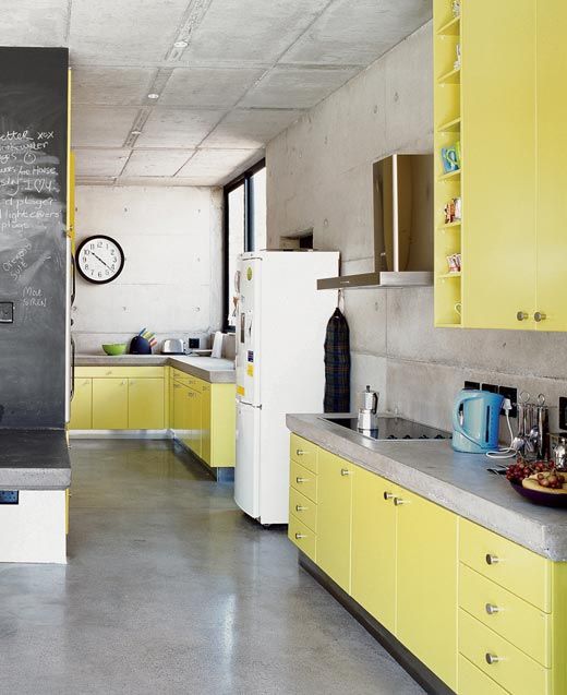 a minimalist light yellow kitchen with concrete countertops and walls is a simple and bright space that looks contrasting