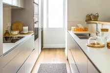 a minimalist tan and white kitchen with sleek cabinetry, a window with much light and a rug is very functional and welcoming