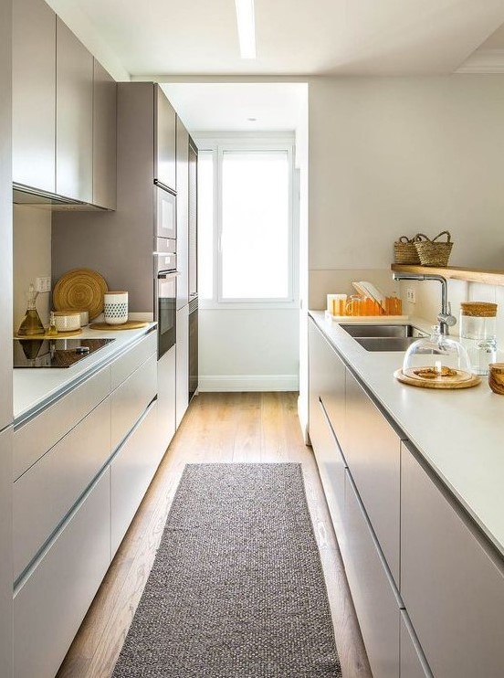 a minimalist tan and white kitchen with sleek cabinetry, a window with much light and a rug is very functional and welcoming