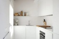 a minimalist white L-shaped kitchen with a wooden ceiling and beams plus a window is very cool and doesn’t look too small