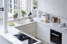 a minimalist white U-shaped kitchen with matching countertops and a backsplash, with built-in appliances