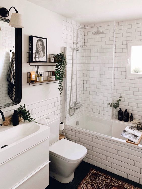 a modern Scandi bathroom with white subway tiles, a white vanity with a sink, shelves, a mirror with a lamp