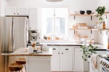 a modern boho U-shaped kitchen with white cabinets, butcherblock countertops, corner shelves and greenery