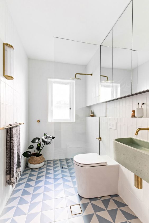 a modern meets Scandinavian bathroom with white skinny tiles, blue and white geo ones, a shower space, a mirror cabinet and a terrazzo sink