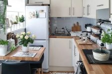 a neutral L-shaped kitchen with grey tiles, butcherblock countertops and potted greenery and blooms