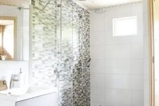 a neutral Nordic bathroom with a wooden ceiling, a mosaic tile wall and a pebble floor and an off-white vanity
