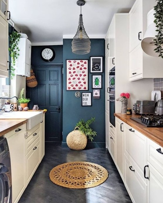 a neutral kitchen with navy walls, a pendant lamp, potted greenery, wooden countertops and a bright gallery wall