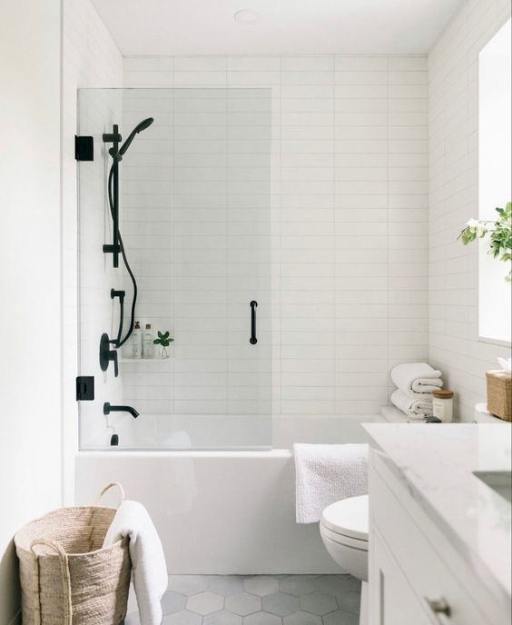 a pretty Scandinavian bathroom with skinny tiles, a white vanity, black fixtures, a basket, white towels