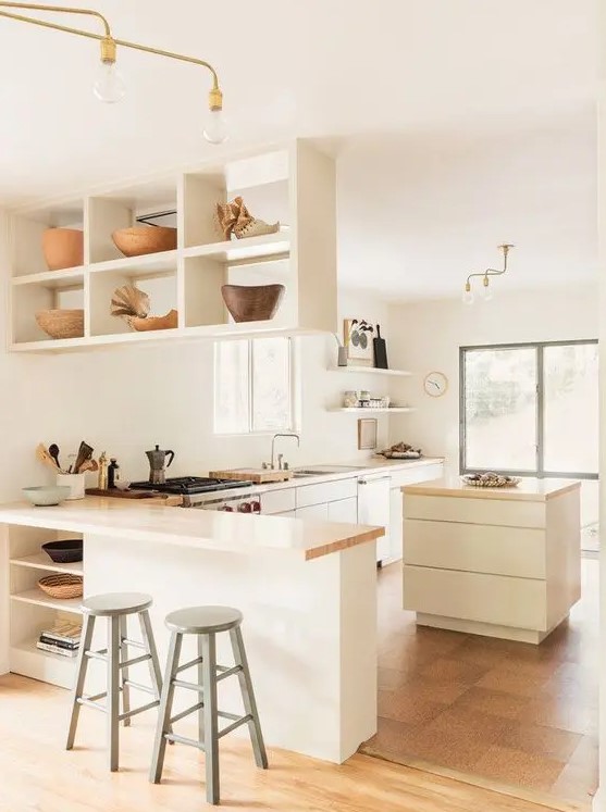 A pretty modern and neutral L shaped kitchen with a suspended shelf, small kitchen island and butcherblock coutnertops