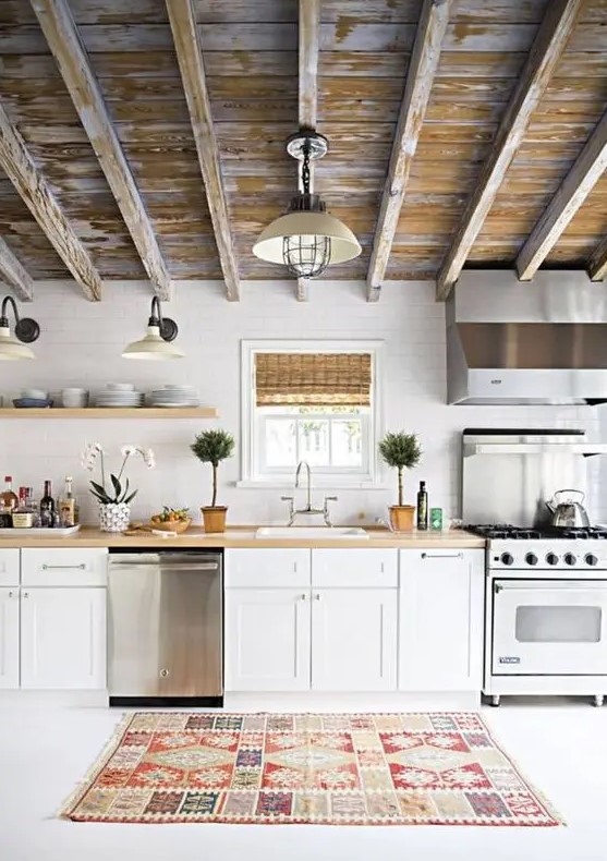 A pretty one wall kitchen with white cabinets, butcherblock countertops and a shabby chic ceiling is very welcoming.