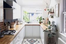 a pretty small kitchen with white cabinets, butcherblock countertops, potted plants and a printed rug