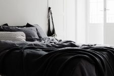 a relaxed Nordic bedroom with a bed with black bedding and a poster on the wall – who needs more for comfy sleeping