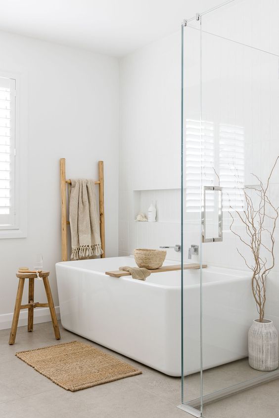a serene Scandinavian bathroom with a bathtub, a shower space, a niche, a stool, a ladder, a shelf and some branches