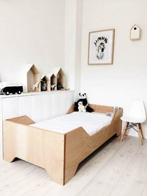 a serene Scandinavian kid's room with a sleek storage unit, a wooden bed, a white chair, some mini houses with toys