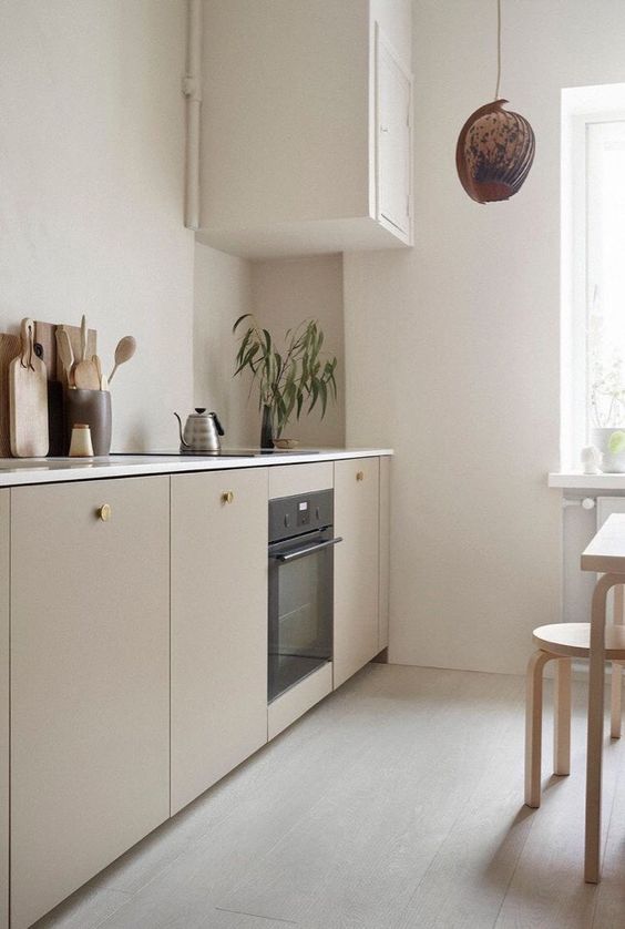 a serene Scandinavian kitchen with greige cabinets, white countertops, MDF dining furniture, a pendant lamp and greenery