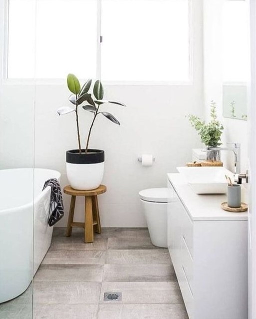 a small Nordic bathroom with a wood tiile floor, a white vanity, an oval tub and potted greenery
