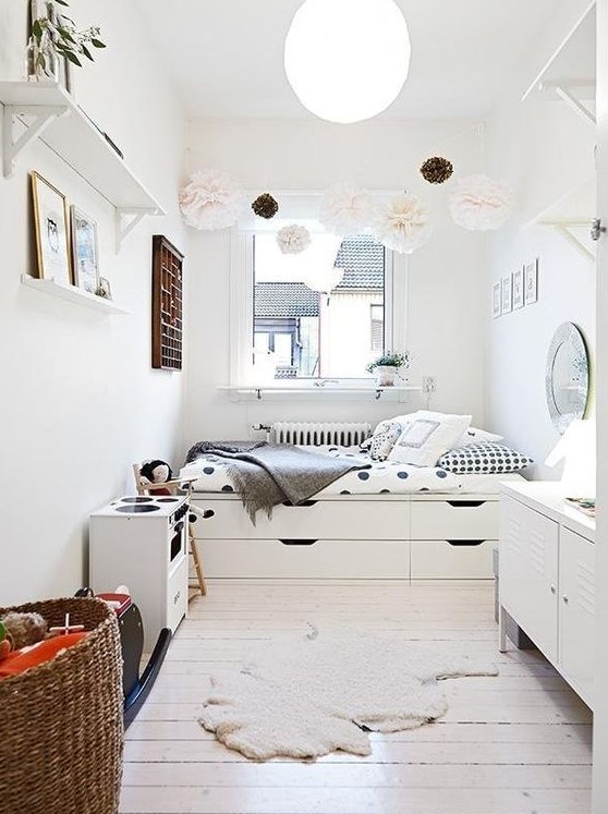 a small Nordic bedroom with a storage bed, a pompom garland, storage units and open shelves