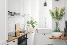 a small Nordic kitchen with white cabinets, black hardware, butcherblock countertops and white tiles plus wood and metal stools