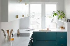 a small and chic tow-tone kitchen with gold handles and a gold pendant lamp plus potted greenery