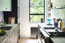 a small galley kitchen with grey stone countertops, open shelves, some appliances and a small window with a black frame