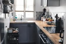 a small graphite grey L-shaped kitchen with a catchy printed backsplash and butcherblock countertops is a cool space