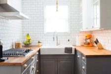 a small grey farmhouse kitchen with butcherblock countertops and white tiles on the walls is chic
