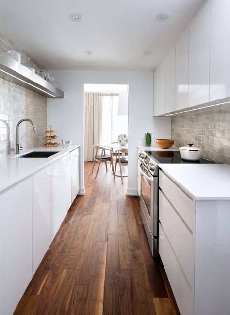 a small minimalist galley kitchen in white, with sleek cabinetry, grey tiles for backsplashes and some open shelves