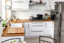 a small white kitchen with butcherblock countertops, neutral handles and pendant lamps plus an eating zone