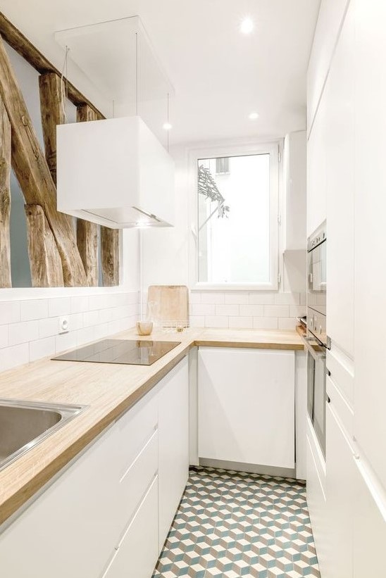 a small white minimalist U shaped kitchen with butcherblock countertops, white subway tiles and rough wood for deocr