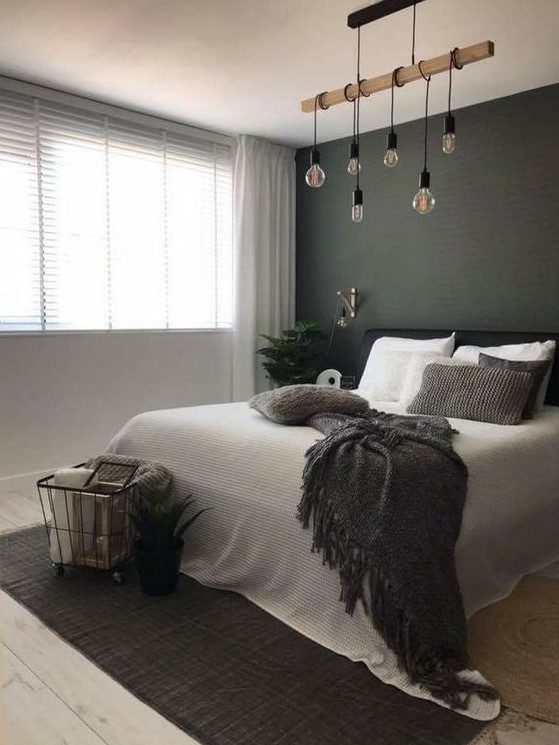 a stylish Scandi bedroom with a black statement wall, a black bed, a hanging piece with bulbs and a rug