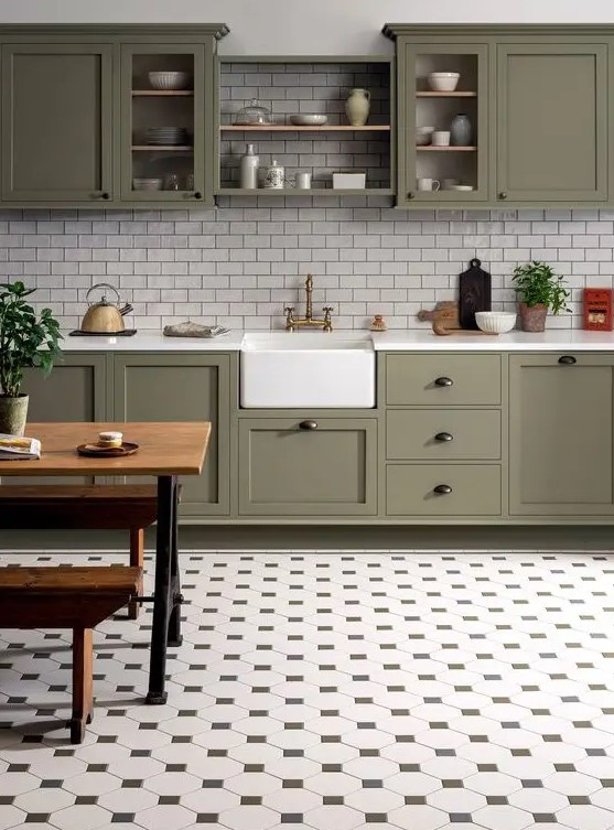 A stylish farmhouse kitchen features olive green cabinets and white subway tiles. A charming tile floor enhances the rustic look. A cozy dining set adds to the inviting atmosphere.