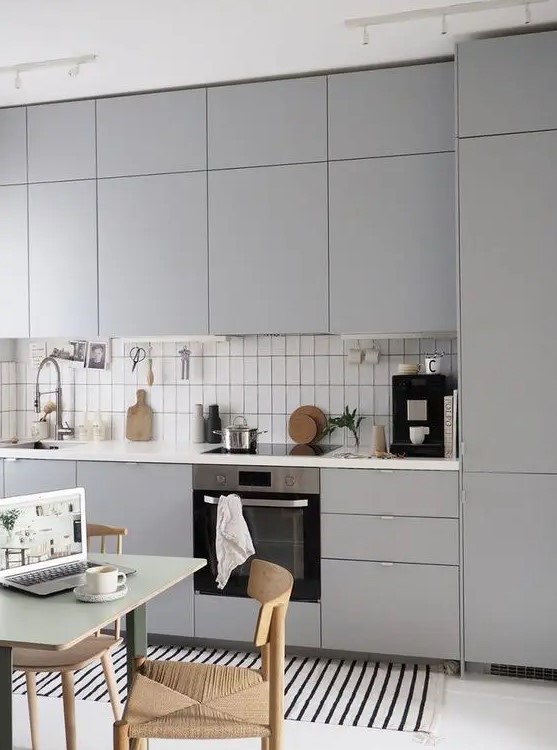 A stylish grey contemporary one wall kitchen with a white tile backsplash and a white countertop is a chic space.