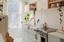 a stylish mid-century modern kitchen with olive green and blonde wood cabinetry, with a skinny tile backsplash and white countertops