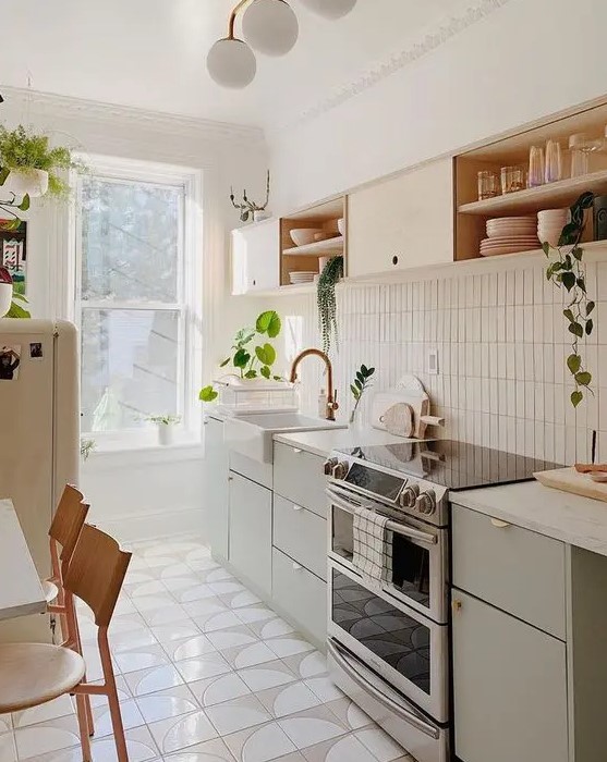 A stylish mid century modern kitchen with olive green and blonde wood cabinetry, with a skinny tile backsplash and white countertops