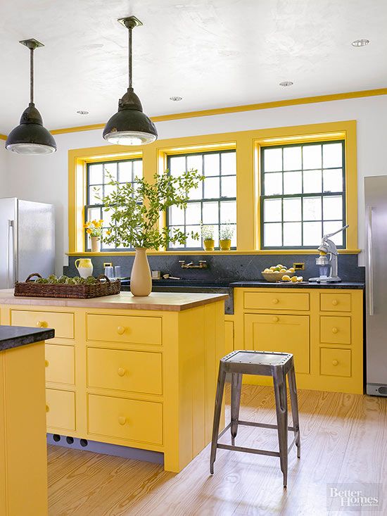 a sunny yellow kitchen with graphite grey stone countertops, grey metal stools and black pendant lamps