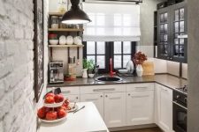 a tiny L-shaped kitchen with two-tone cabinets, dark countertops and a black pendant lamp plus patterned tiles