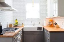a two tone kitchen in grey and white, with butcherblock countertops and a white subway tile backsplash is very cozy