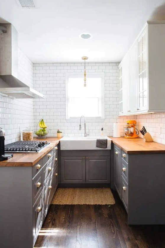 a two tone kitchen in grey and white, with butcherblock countertops and a white subway tile backsplash is very cozy