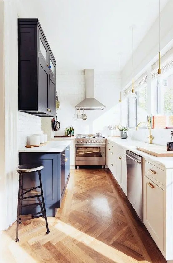 a two-tone kitchen in navy and white with white stone countertops, gold and brass touches and a glazed wall