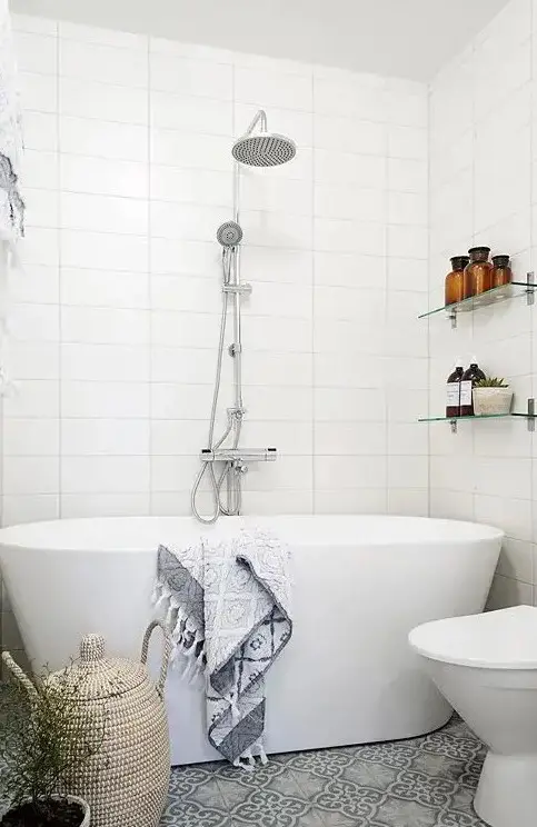 a very small bathroom with a patterned grey tile floor and a freestanding tub for a chic look