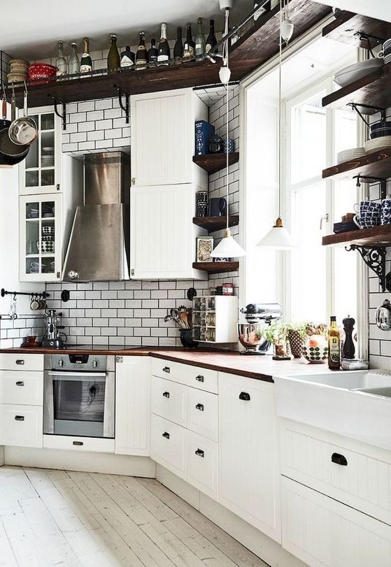 A vintage inspired Nordic kitchen with a ceiling shelf, white tiles, white vintage cabinets and rich stained countertops