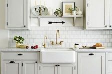 a vintage neutral kitchen with elegant cabinets, a white tile backsplash, a colorful tile floor and black wall lamps