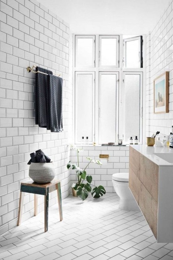 a welcoming Scandi bathroom with vintage touches, a wooden vanity =, towels and a large window for natural light
