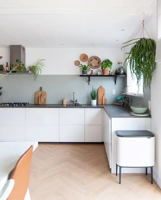 a white L-shaped boho kitchen with a grey backsplash, grey stone countertops, potted greenery is lively and cool