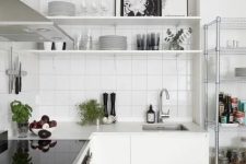 a white Nordic kitchen with a white tile backsplash, stainless steel appliances is a very airy space
