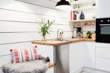a white Scandinavian kitchen with butcherblock countertops, black pendant lamps and potted greenery